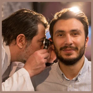 An audiologist examines a man's ear.