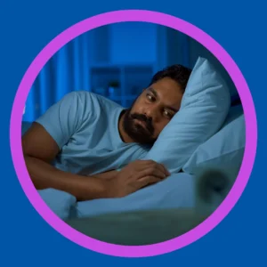 A wide awake man lies in his bed. 