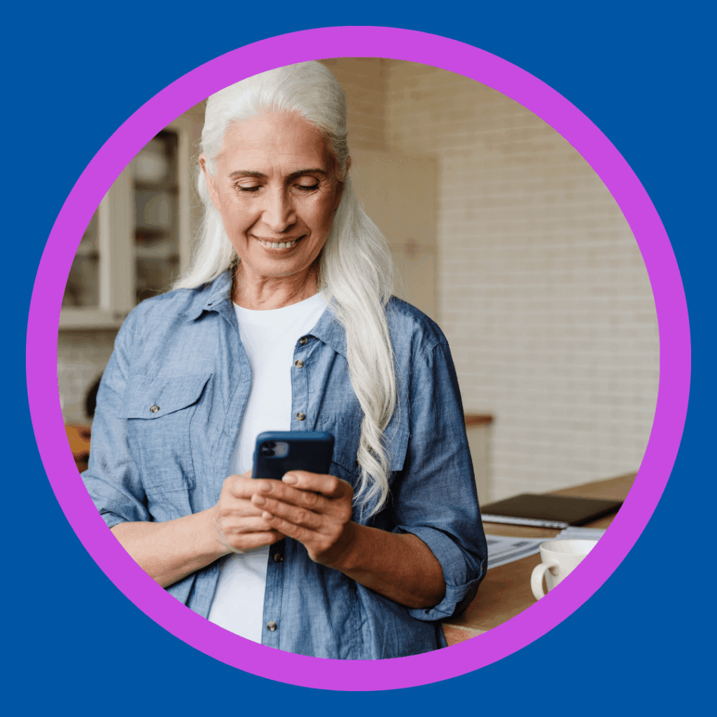 An older woman smiles at her phone.