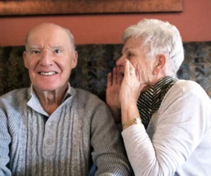 A woman yells into a man's ear. 