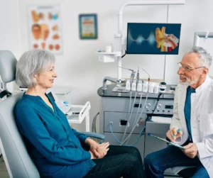 An audiologist talks to a woman in his office. 