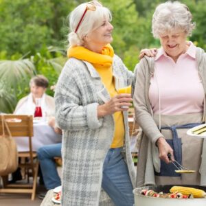 Two older women chat at a backyard party.
