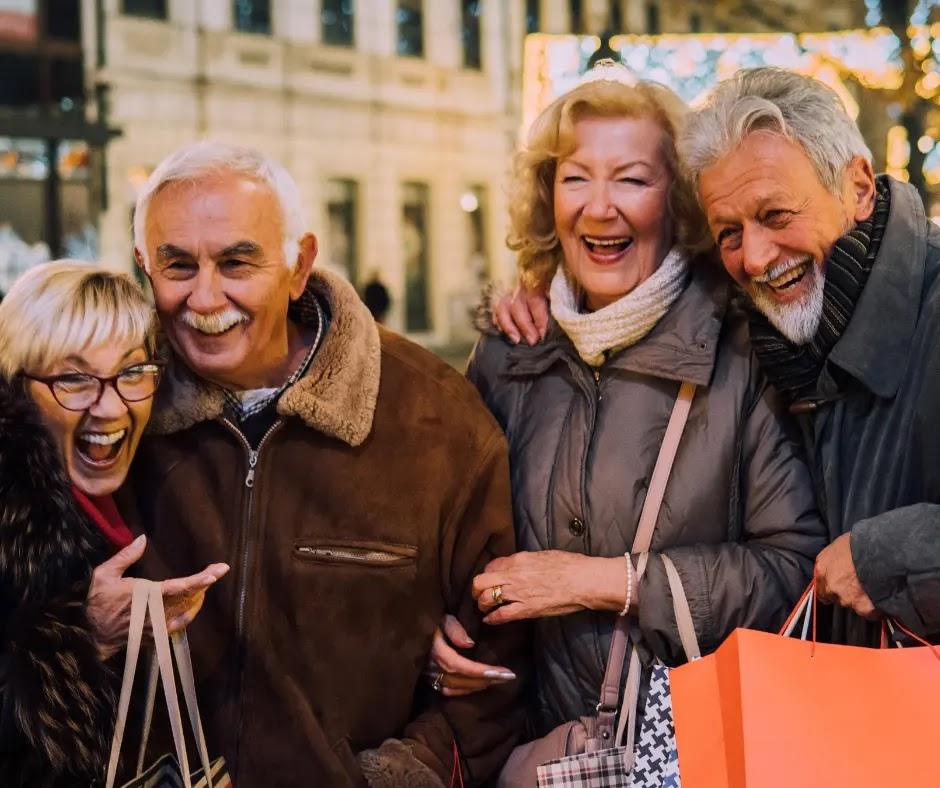 Two older couples laugh together in the city.