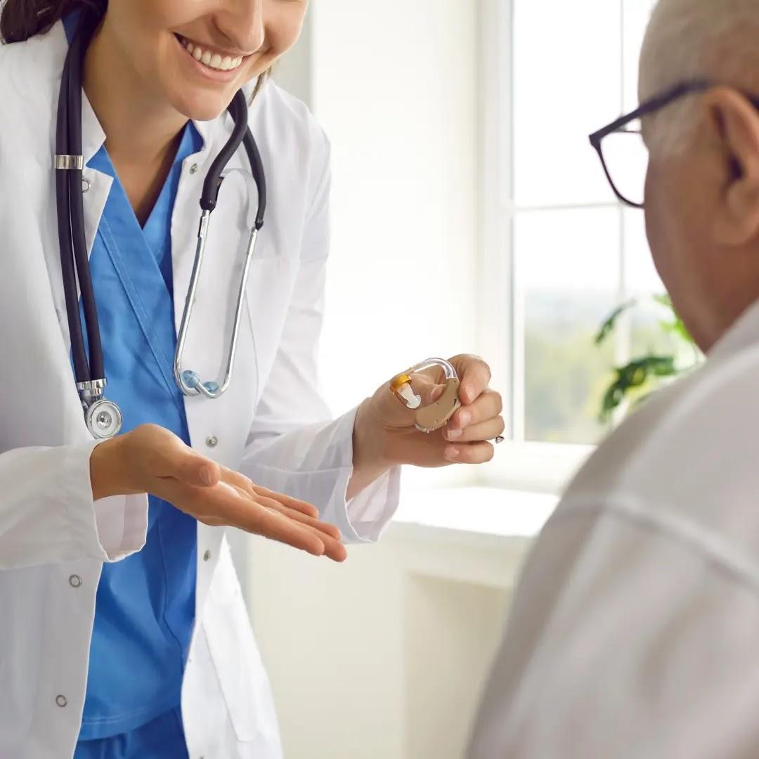 An audiologist talks to a man about his hearing aid.