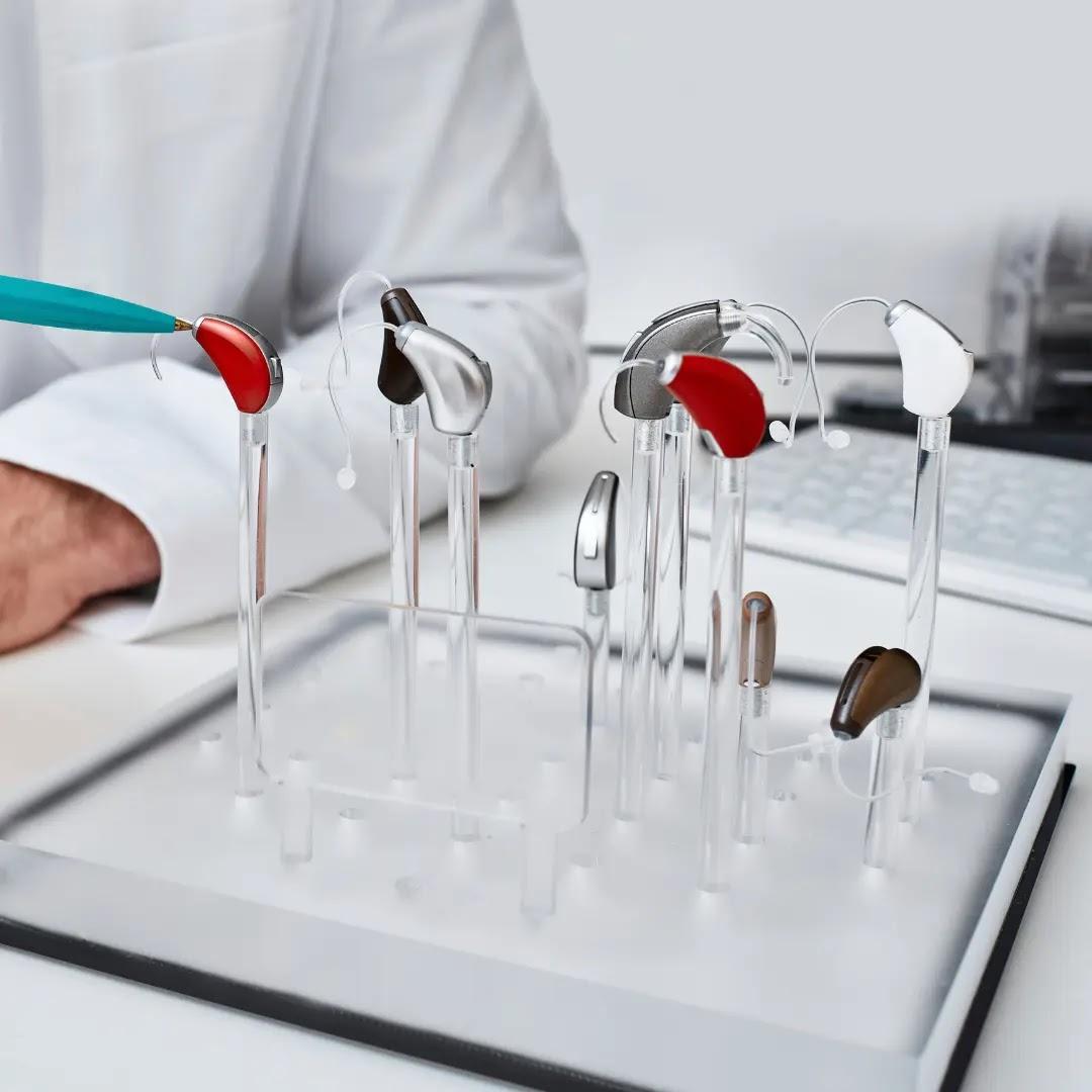 Many different hearing aids sit on a clear display.