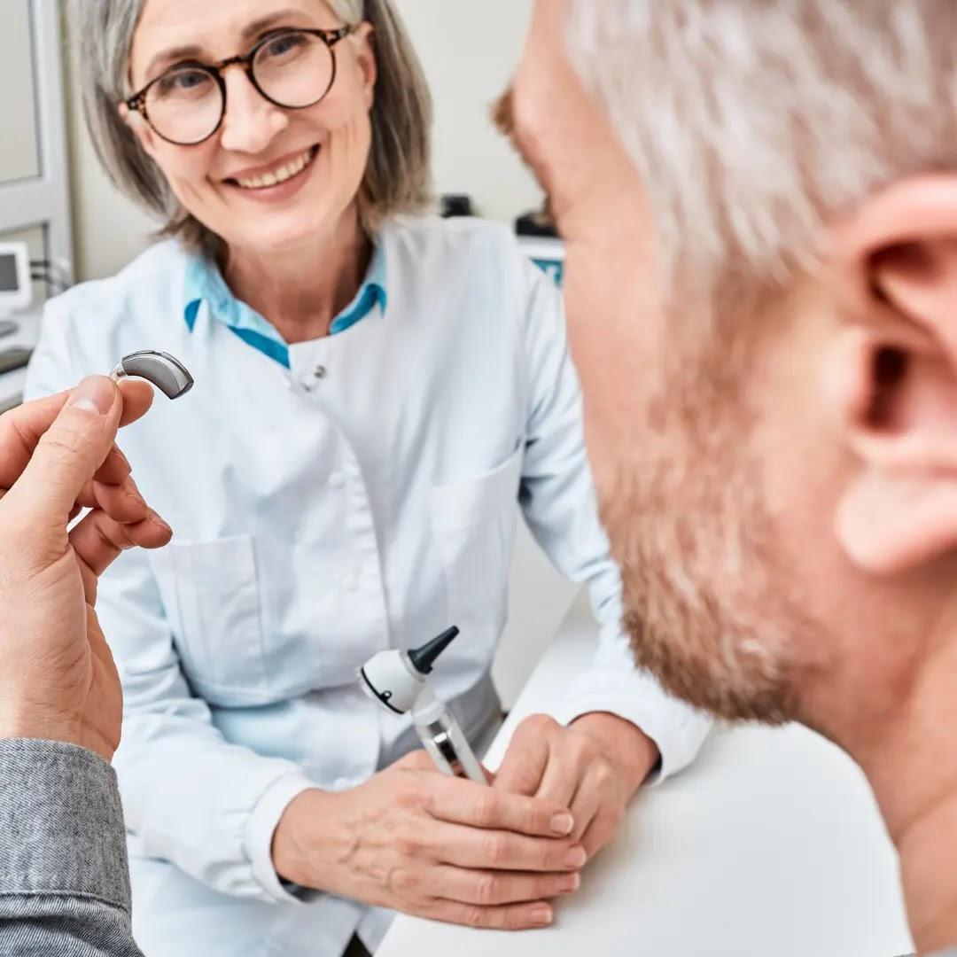 A man shows his hearing aid to his audiologist.