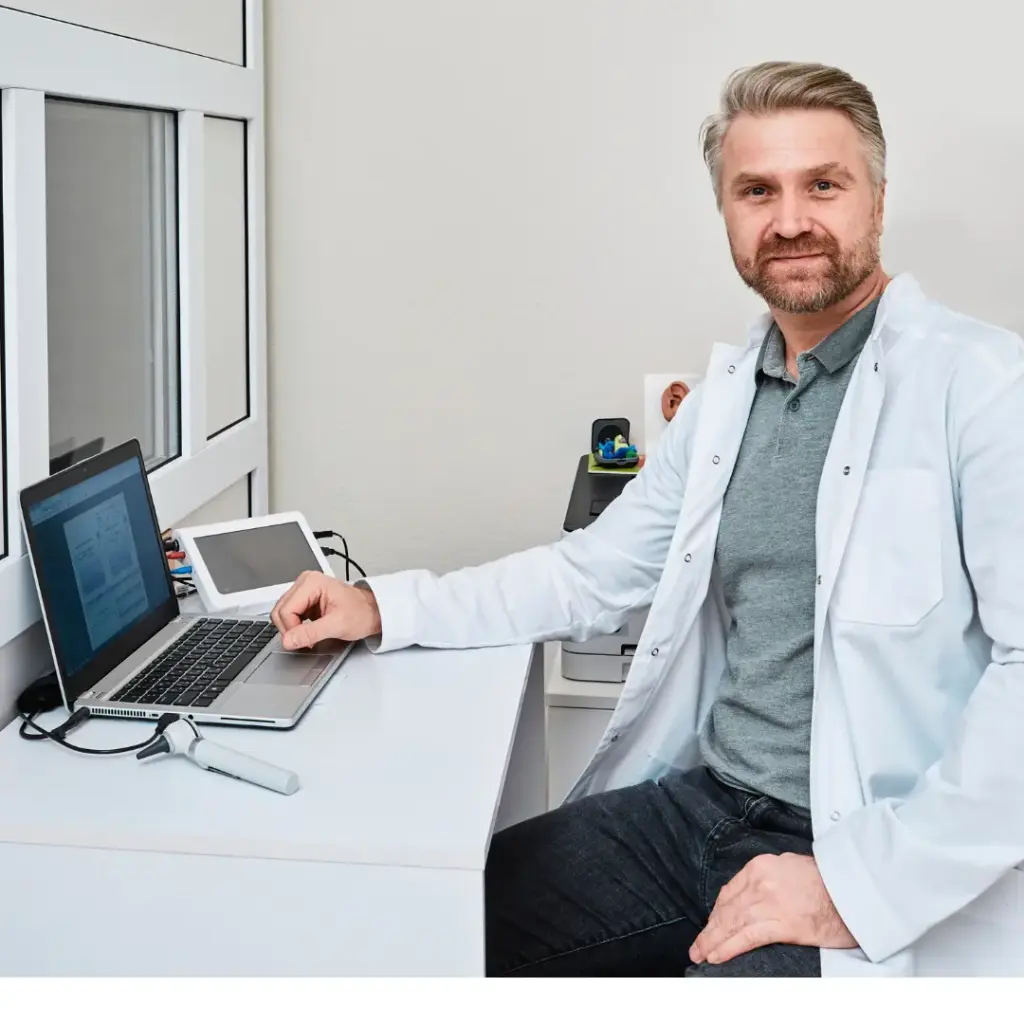 An audiologist smiles from his office.