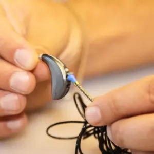 Hands fix a hearing aid. 