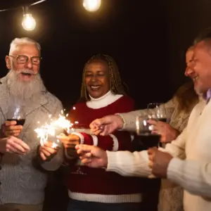 Older friends light sparklers and drink wine. 