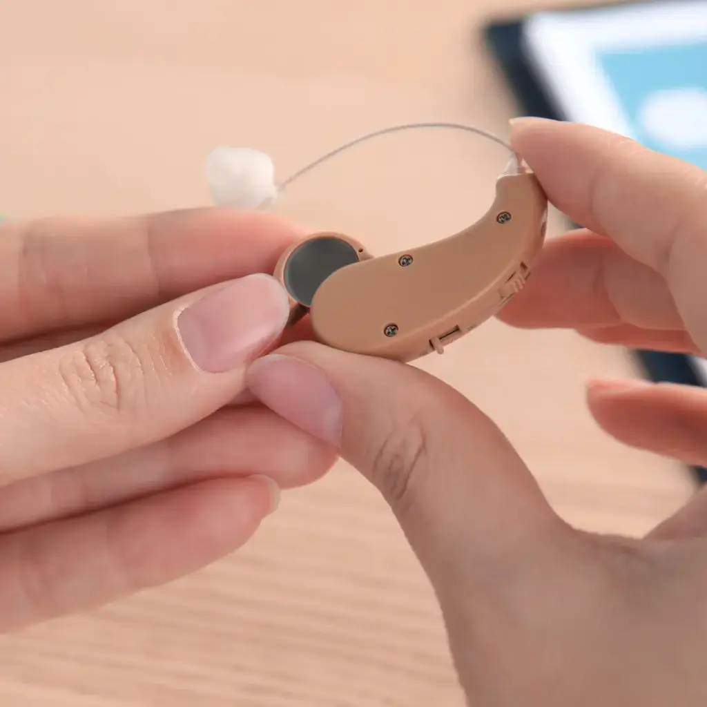 Hands place a component in a hearing aid.
