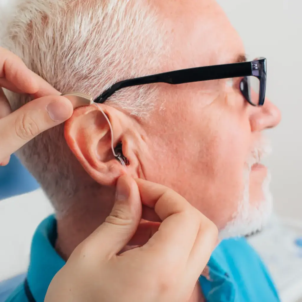 A hearing specialist fits a hearing on an older man.