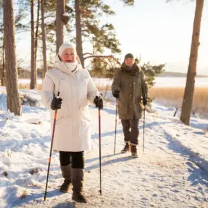 An older couple wears hats over their hearing aids as they go on a winter hike.