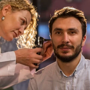 An audiologist examines a patient’s ear with an otoscope. 