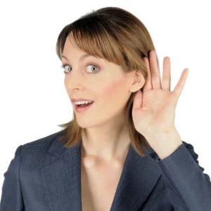 A woman cups her hand around her ear to hear better. 