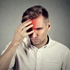 A man holds his head and grimaces. 