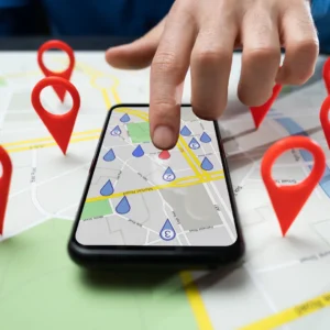 A finger points to a cell phone screen with marked map locations.