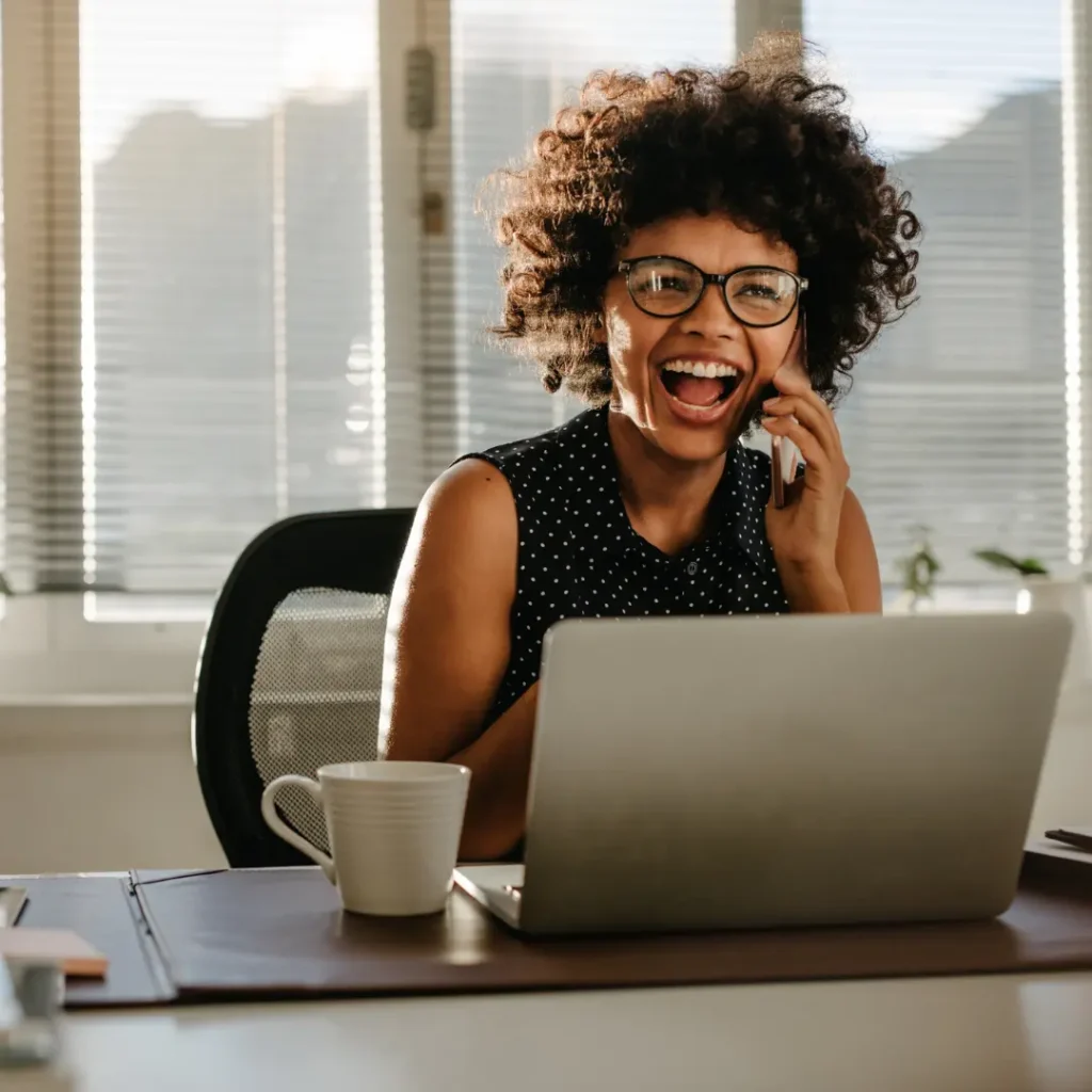 A woman laughs while on the phone.