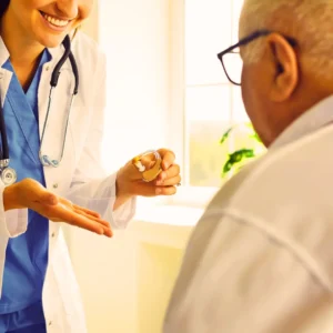 A hearing care provider shows her patient a hearing aid.