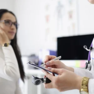 A hearing aid specialist takes notes while talking to her patient.