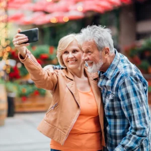 An older couple smiles as they pose for a selfie.