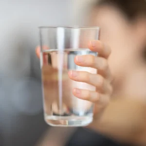 A hand holds a full glass of water.