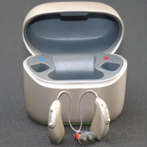Durable hearing aids stand in front of their charging case.