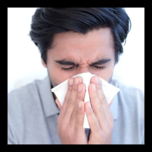 A man blows his nose into a white tissue. 