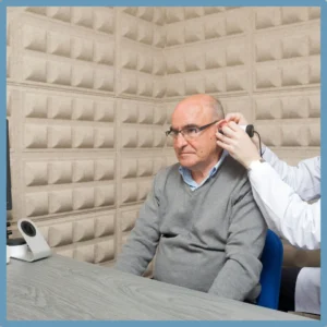 An older man is having his hearing tested in a soundproof room. 