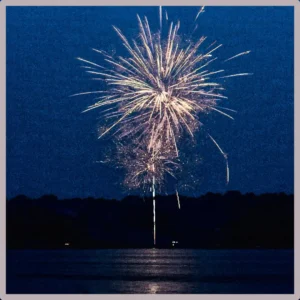 A view of a fireworks display from across a large lake.