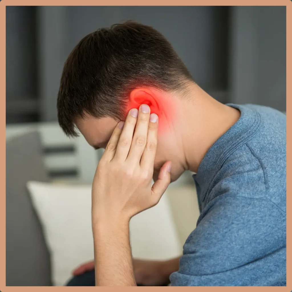 A man holds his bright red ear and looks down in pain.
