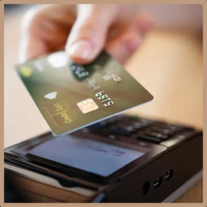 A hand holds a credit card over a payment system. 