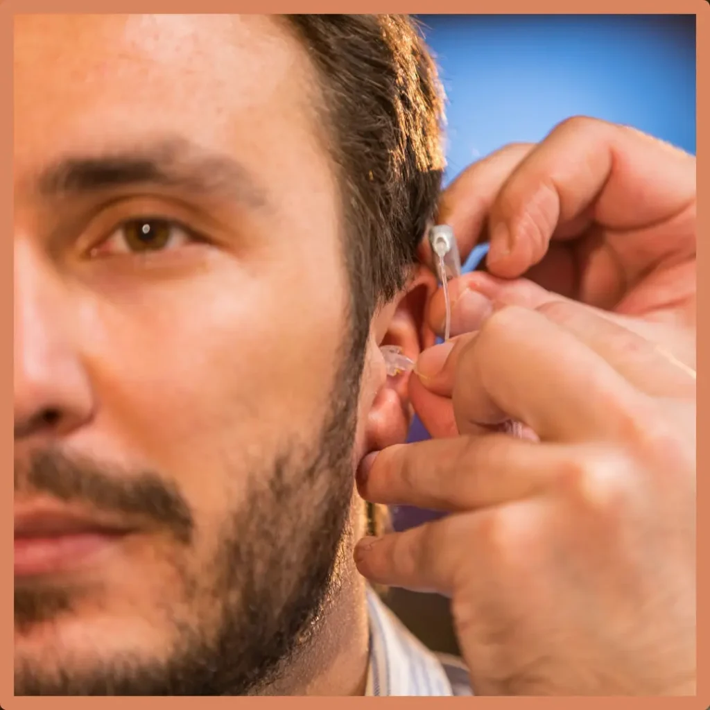 An audiologist puts a hearing aid on a patient.