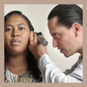 An audiologist looks into a woman’s ear. 
