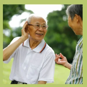 A man cups his ear to hear better while chatting with a friend. 