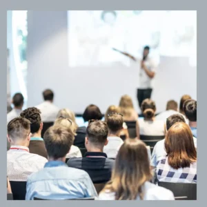 People listen to a speaker in a conference room.
