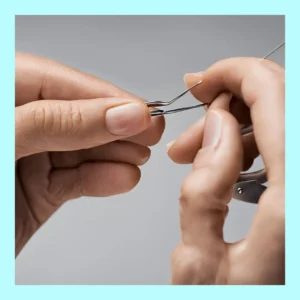 Hands use a tweezer on a hearing aid. 