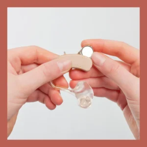 Hands put a battery into a hearing aid.