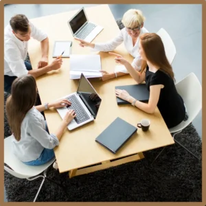 People talk and type at the same table in an office. 