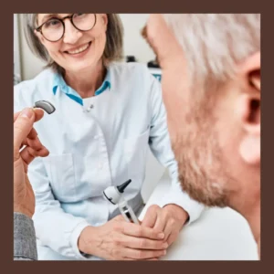 A man looks at a hearing aid with his audiologist. 