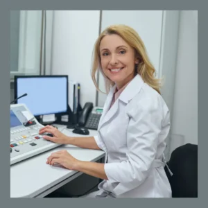 An audiologist smiles in a hearing test area. 