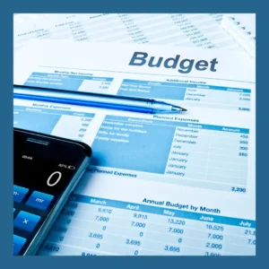 A budget worksheet, a calculator and a pen sit on a table.