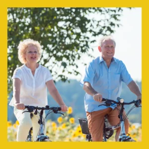 An older couple rides bikes together outside.