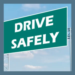 A green highway sign says “Drive Safely” against a blue sky.