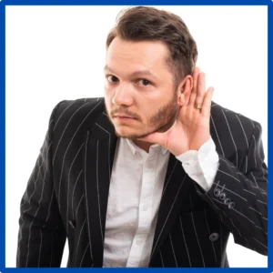 A man in a suit cups his hand around his ear to hear.