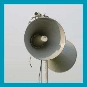An outdoor loudspeaker stands against a gray sky.