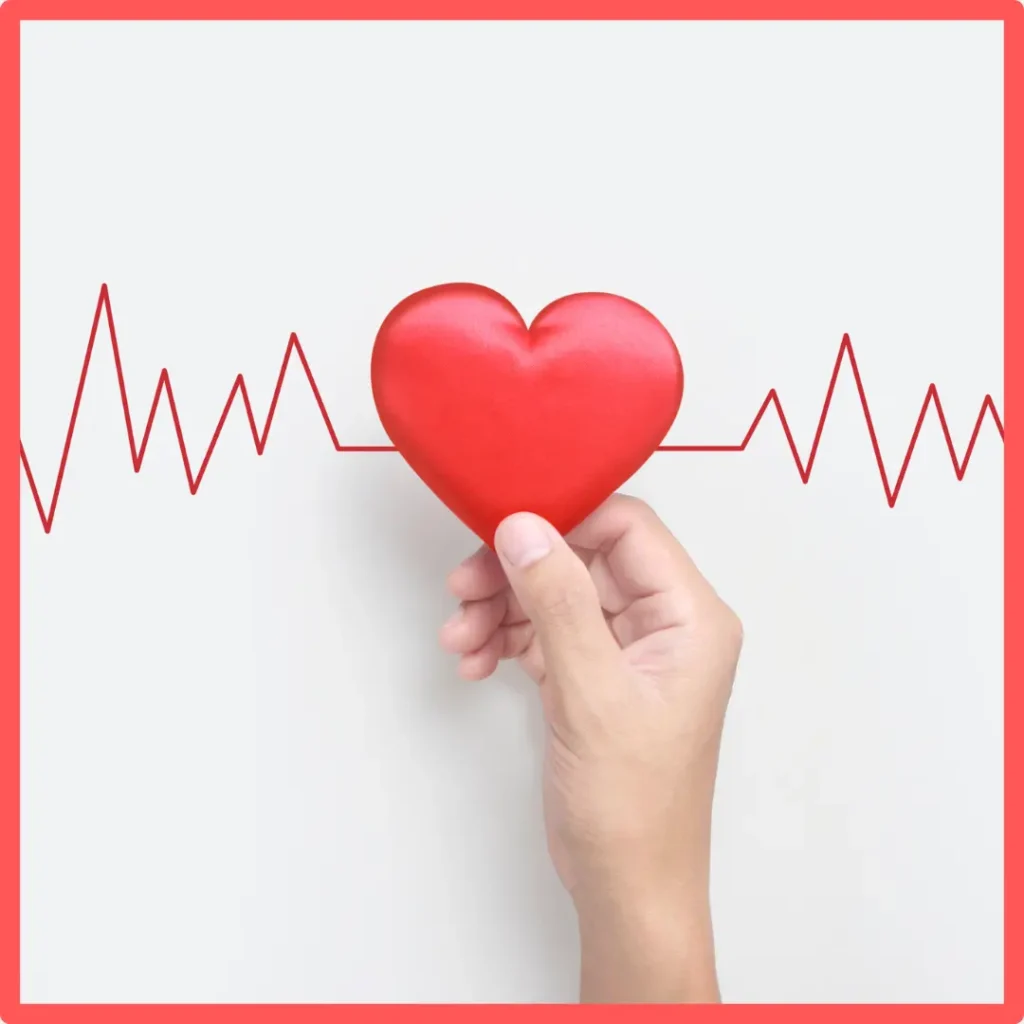 A hand holds a heart against an echocardiogram.
