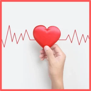 A hand holds a heart against an echocardiogram.