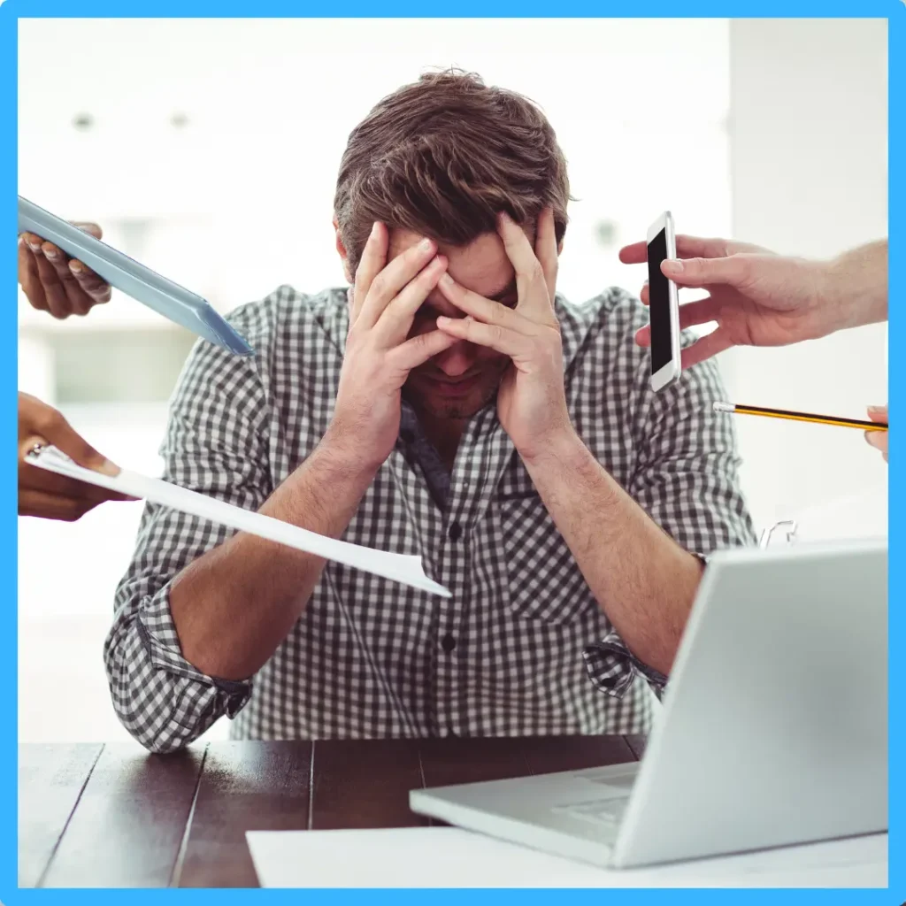A man holds his head while phones and papers are shoved in his face.