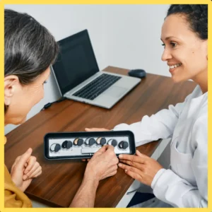 An audiologist consults with a patient at her desk.