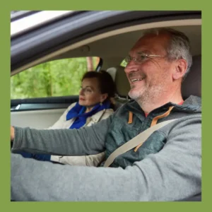 An older man drives a car happily.